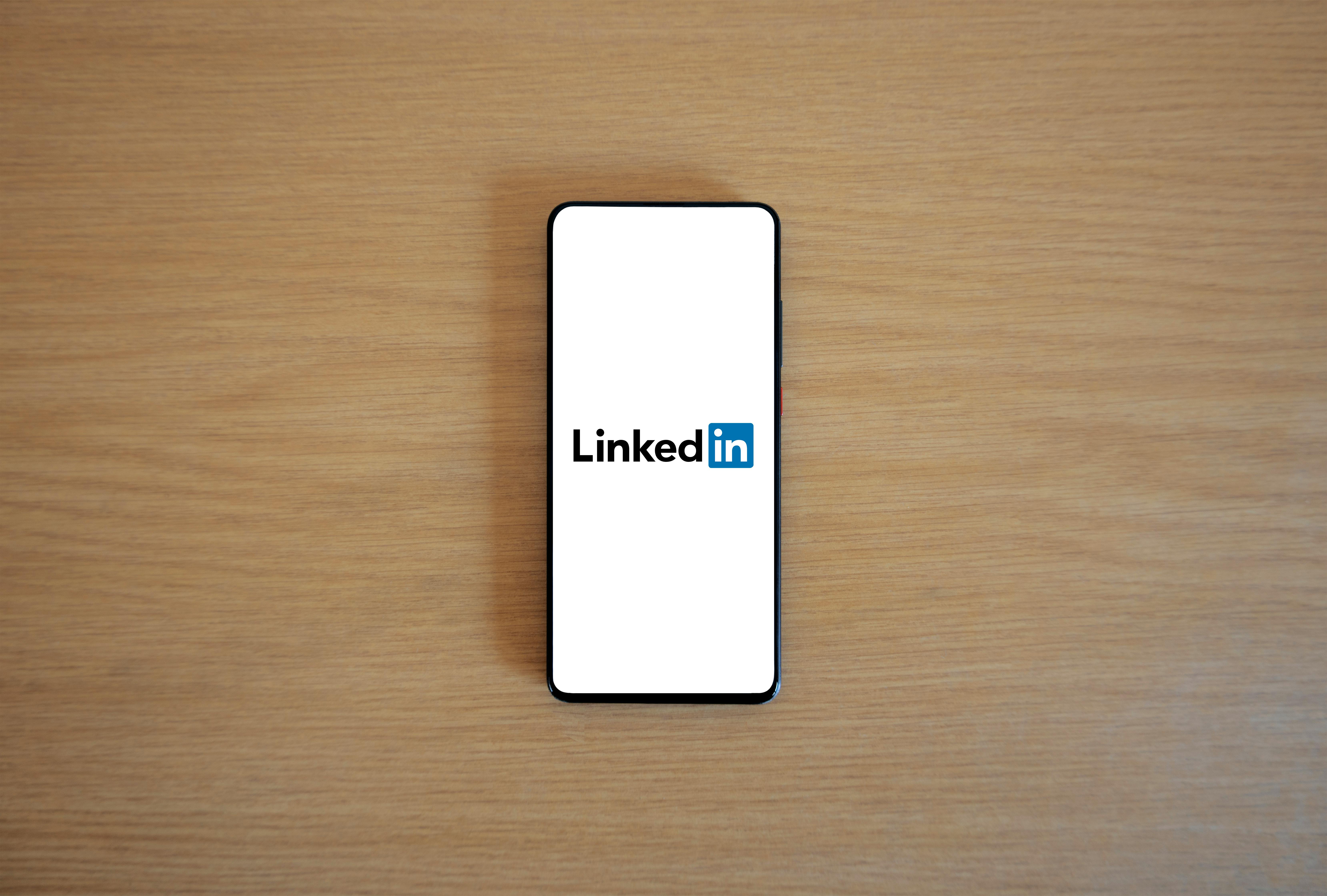 A phone open to the Linkedin logo on a desk